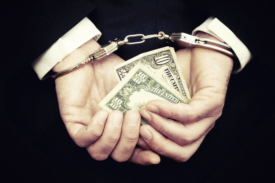 handcuffed man holding $10 bill