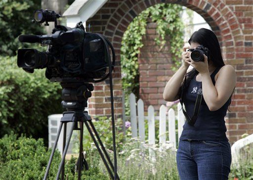 Lulis Leal, of Cedar Grove, N.J., takes photos of 31 Marquette Road in Montclair, N.J., as a television camera stands idol Tuesday, June 29, 2010. The house is where "Richard and Cynthia Murphy" lived before they were arrested by the FBI on Sunday, and along with eight others who are alleged to be secret agents spying for Russia. (AP Photo/Rich Schultz)