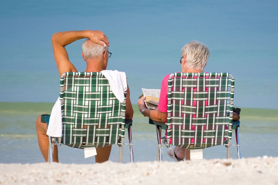 man-woman-sitting-beach-chairs-reading