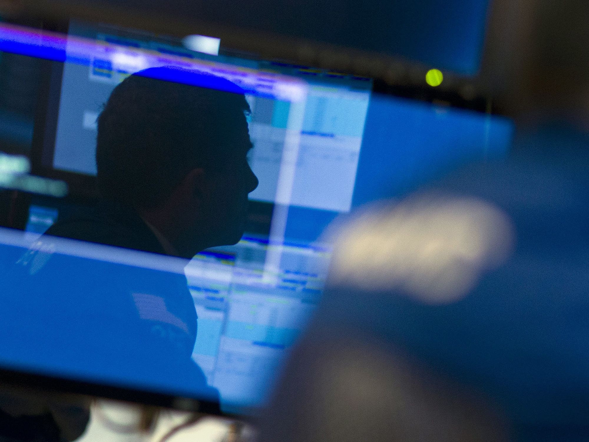 A trader is reflected in a monitor as he works on the floor of the New York Stock Exchange. 