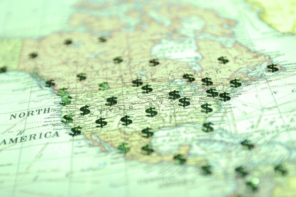 A green-tinted map of North America dotted with shiny green dollar signs