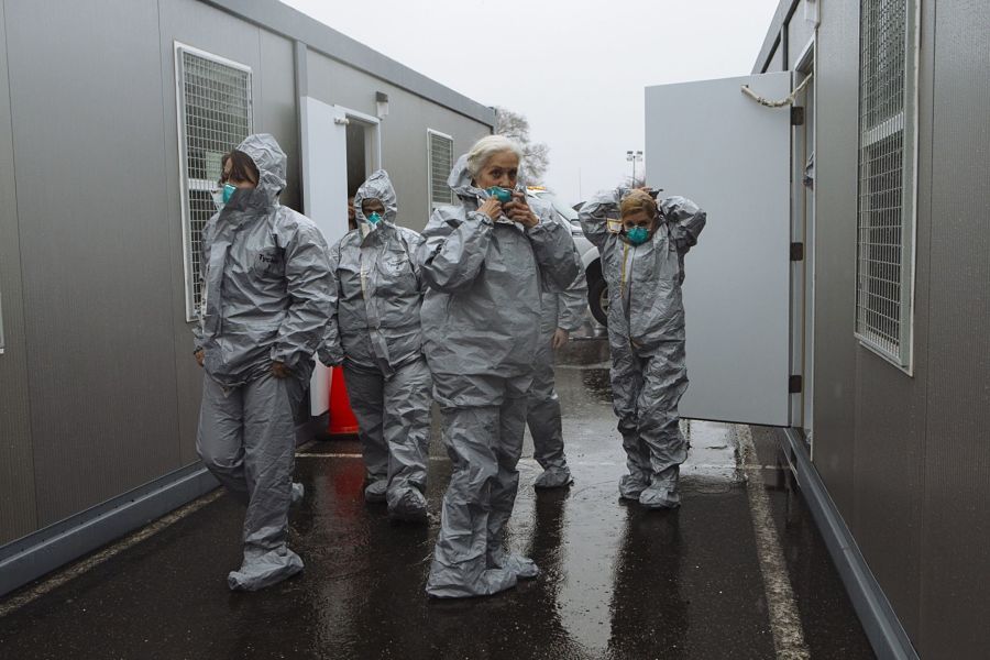 Health care worker in protective suits place masks on their face outside a six lane COVID-19 drive-through testing facility at Glen Island Park in New Rochelle, New York, U.S., on Friday, March 13, 2020. President Donald Trump plans to declare a national emergency on Friday over the coronavirus outbreak, invoking the Stafford Act to open the door to more federal aid for states and municipalities, according to two people familiar with the matter. Photographer: Angus Mordant/Bloomberg