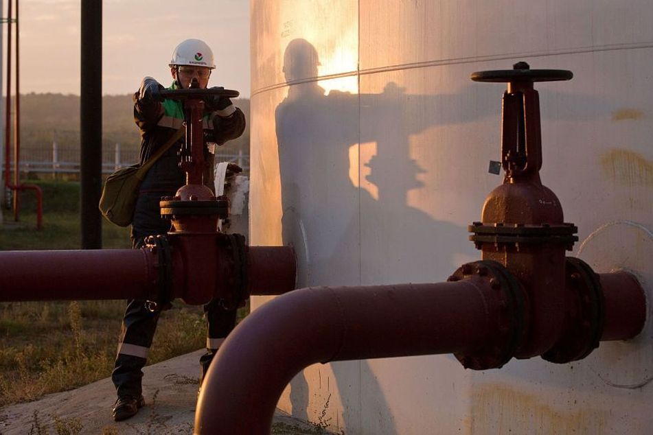 Employee turns valve on pipeline on oil tank