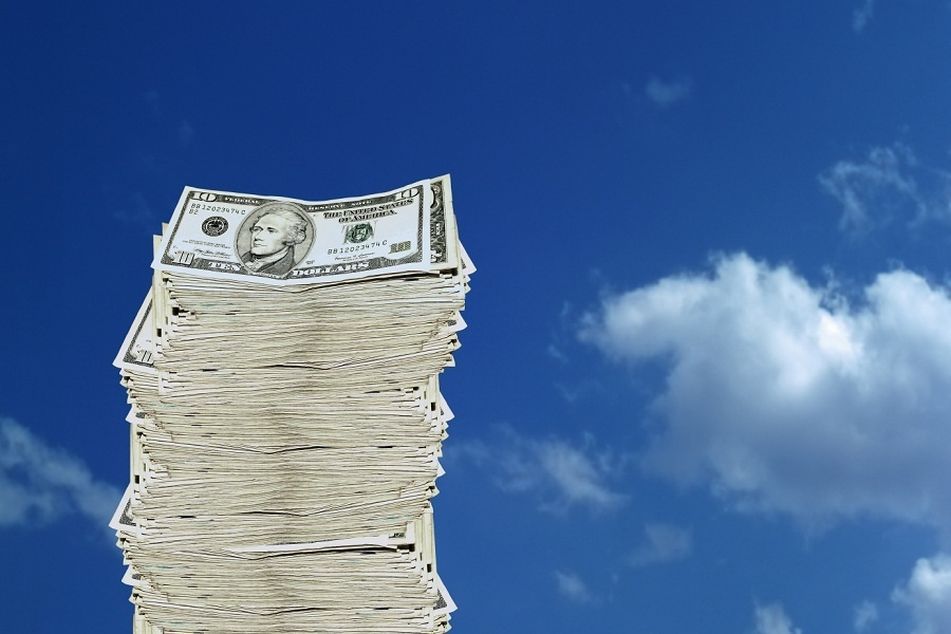 pile-of-dollar-bills-against-blue-sky