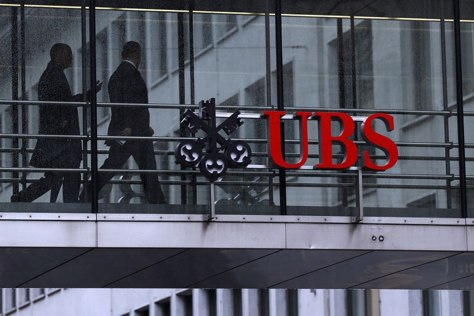 Man silhouette walking past UBS sign