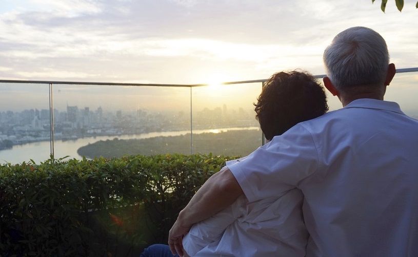 senior looking at sunrise together over city skyline and river