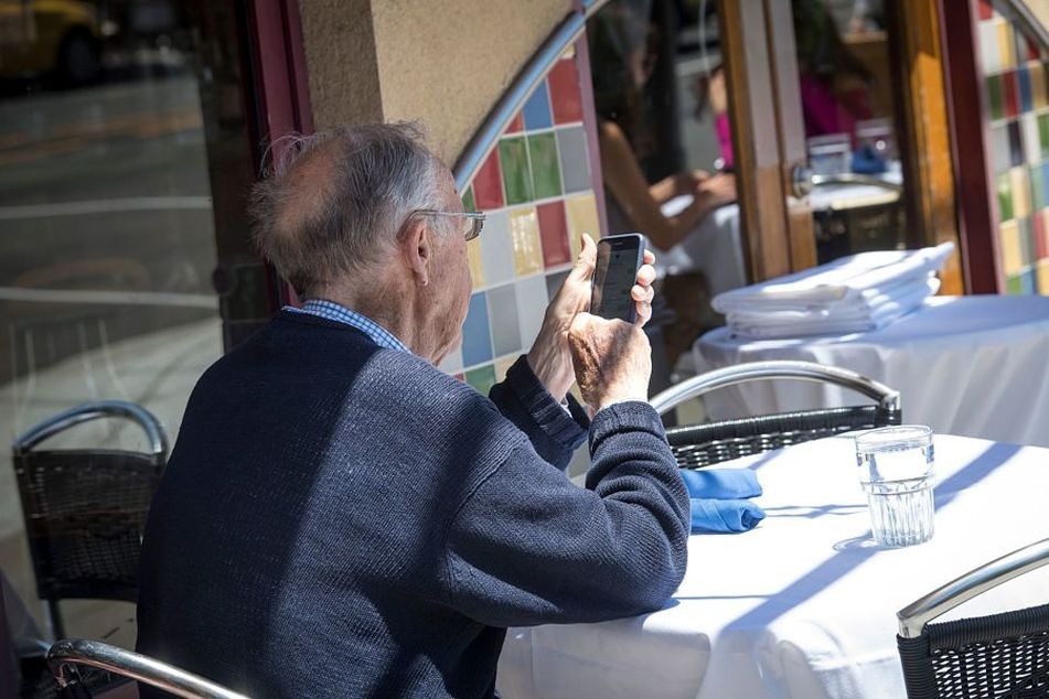 older-man-using-cellphone-at-table