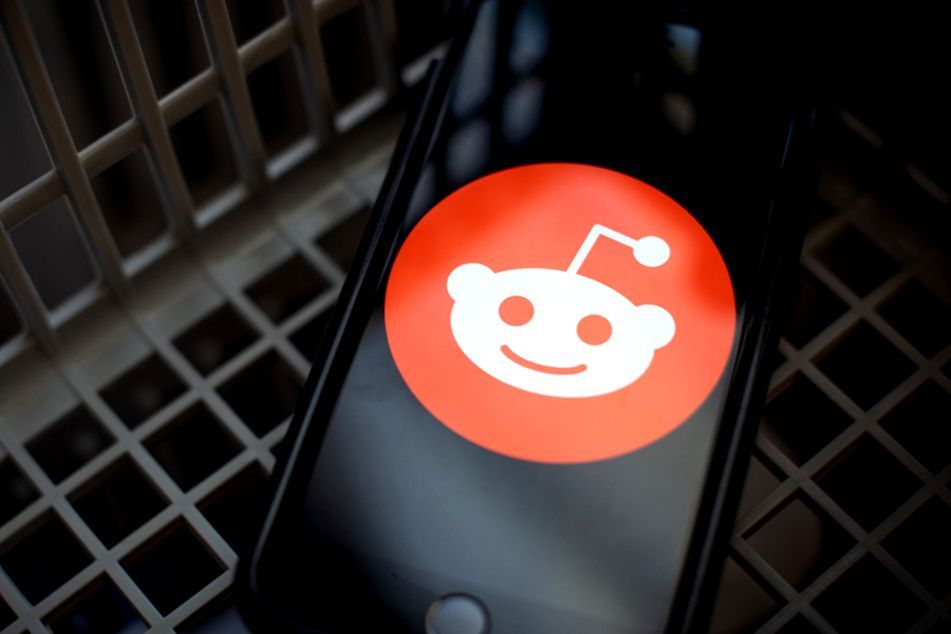 Reddit logo on smartphone near a laptop
