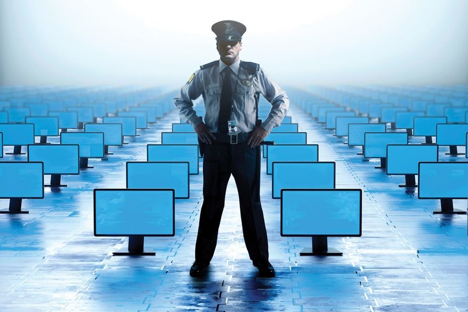 Security officer standing guard over rows and rows of computer monitors