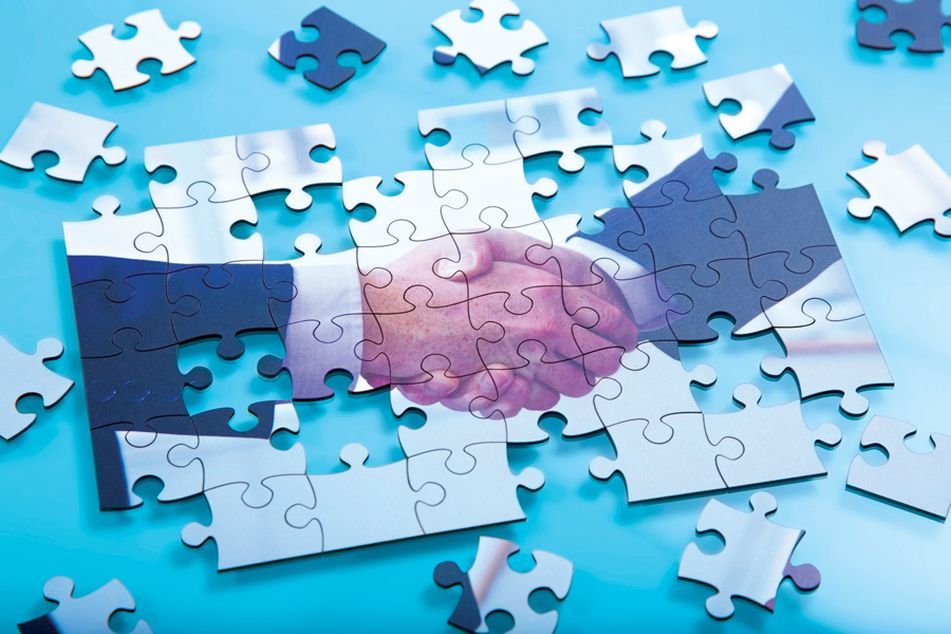 partially assembled jigsaw puzzle shows two businessmen shaking hands