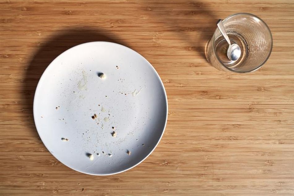 empty plate with crumbs and an empty glass on a table