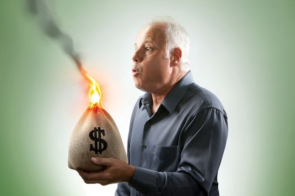 older man holding bag of money on fire