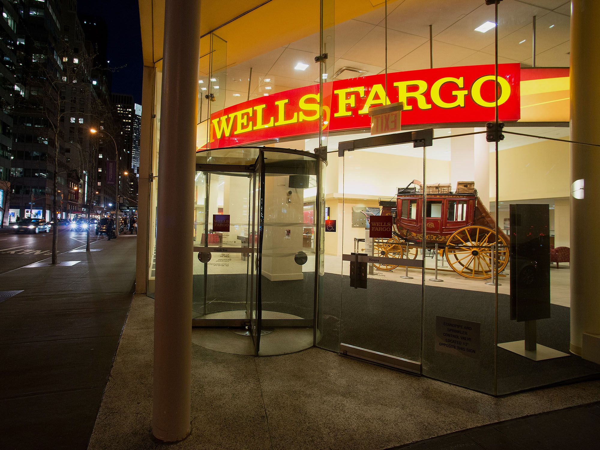 Pedestrians pass in front of a Wells Fargo & Co. bank branch at night in New York. Photographer: Craig Warga/Bloomberg