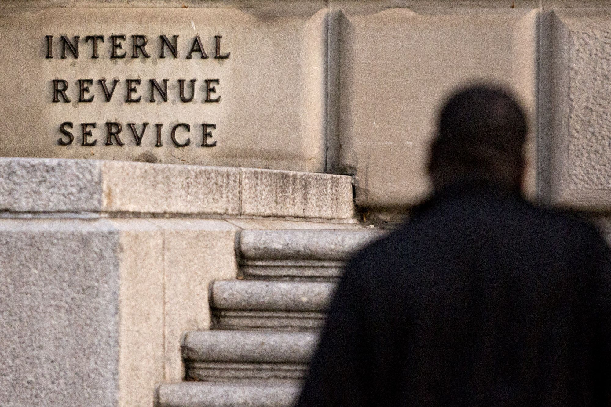 A man walks past the Internal Revenue Service (IRS) headquarters in Washington, D.C., U.S.. Photographer: Andrew Harrer/Bloomberg