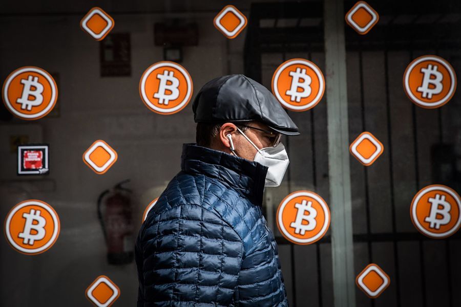 A pedestrian wearing a protective face mask passes a bitcoin automated teller machine (ATM) kiosk in Barcelona, Spain, on Tuesday, Feb. 23, 2021. Bitcoin climbed, aided by supportive comments from Ark Investment Managements Cathie Wood and news that Square Inc. boosted its stake in the cryptocurrency.