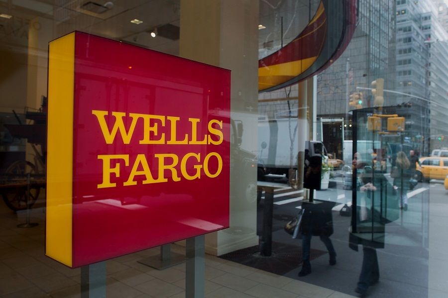 The reflections of pedestrians are seen in the window of a Wells Fargo & Co. bank branch in New York, U.S., on Monday, April 7, 2014. Wells Fargo & Co. is expected to release earnings figures on April 11. Photographer: Craig Warga/Bloomberg