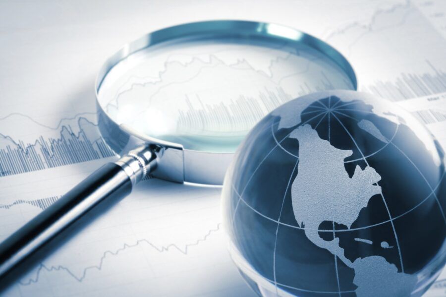 magnifying glass and globe over stock graph document, business concept